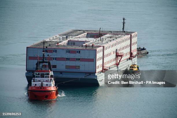 Tug boat Mercia pulls the Bibby Stockholm accommodation barge into Portland in Dorset where it is due to house migrants after travelling from dry...