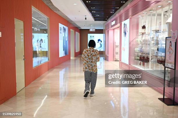 Woman walks past stores in a shopping mall in Beijing on July 18, 2023.