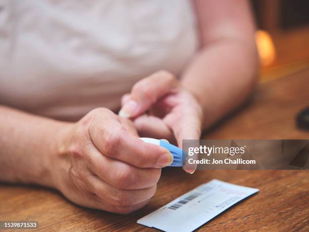 a woman doing a finger prick test at home - glucose stock pictures, royalty-free photos & images