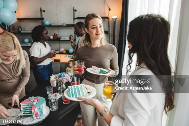 two adult female friends catching up at a gender reveal party - gâteau stockfoto's en -beelden