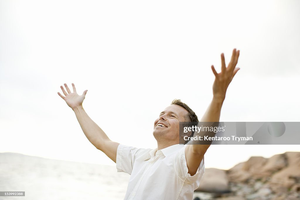 Excited man with arms outstretched on shore