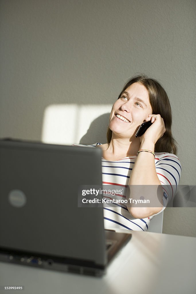 Happy mid adult woman looking up while talking on cell phone