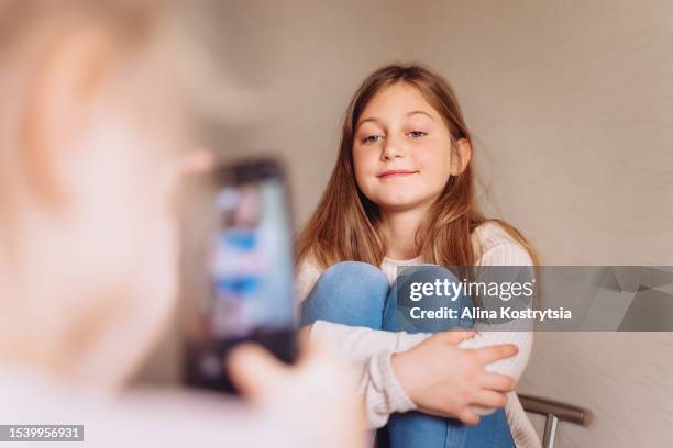 little girl making photo her older sister's using mobile phone - selfie girl stockfoto's en -beelden