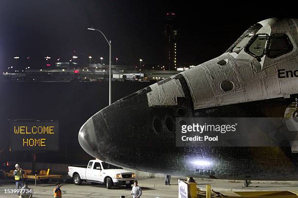 Welcome home sign is displayed on the turn as the space shuttle Endeavour leaves Los Angeles International Airport in the early hours of October 12,...