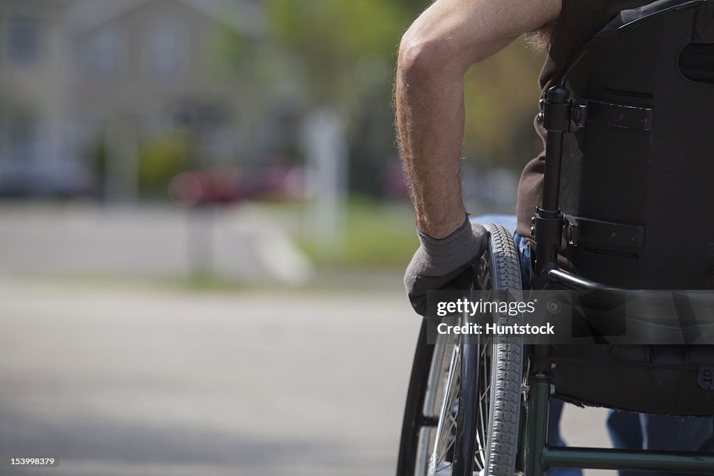 Man with spinal cord injury in a wheelchair on street corner