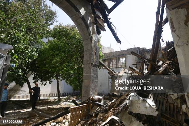 Two Syrian men stand outside the damaged historic Beit Khaled al-Adhem, one of four buildings damaged by a fire that broke out on the weekend, in the...