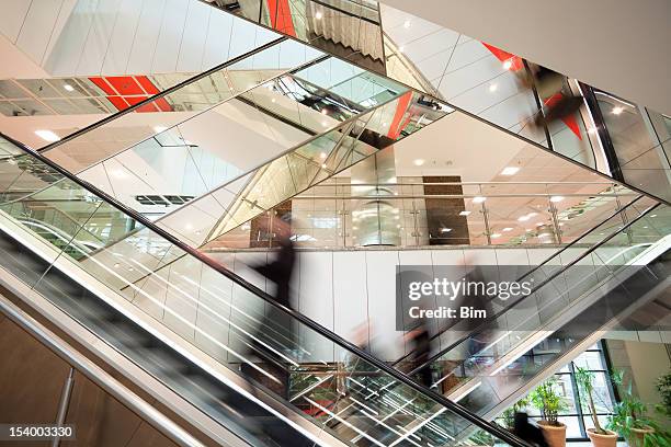 blurred people on escalator in modern glass interior - shopping abstract stockfoto's en -beelden