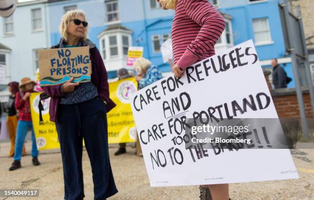 Protestors hold placards welcoming refugees to Portland Port, following the arrival of the Bibby Stockholm asylum seeker accommodation barge, in...