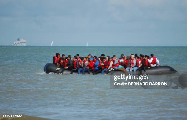 Migrants sit onboard an inflatable boat before attempting to illegally cross the English Channel to reach Britain, off the coast of Sangatte,...