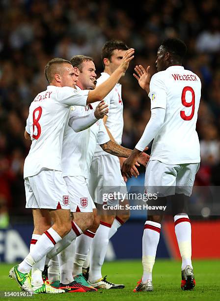 Captain Wayne Rooney of England celebrates with Tom Cleverley and Danny Welbeck as he scores their first goal from a penalty during the FIFA 2014...