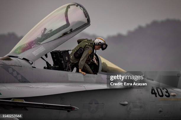 Marine enters the cockpit of an F/A-18 Hornet fighter during the bi-annual Marine Aviation Support Activity 23 at the airport of a former US naval...