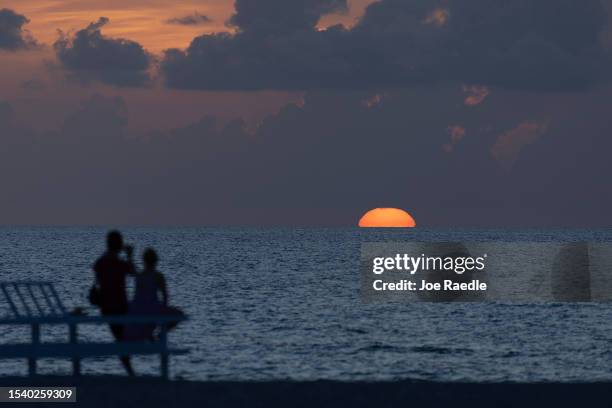 People enjoy the sunrising over the Atlantic Ocean on July 13, 2023 in Miami Beach, Florida. With triple-digit heat indices over South Florida, the...