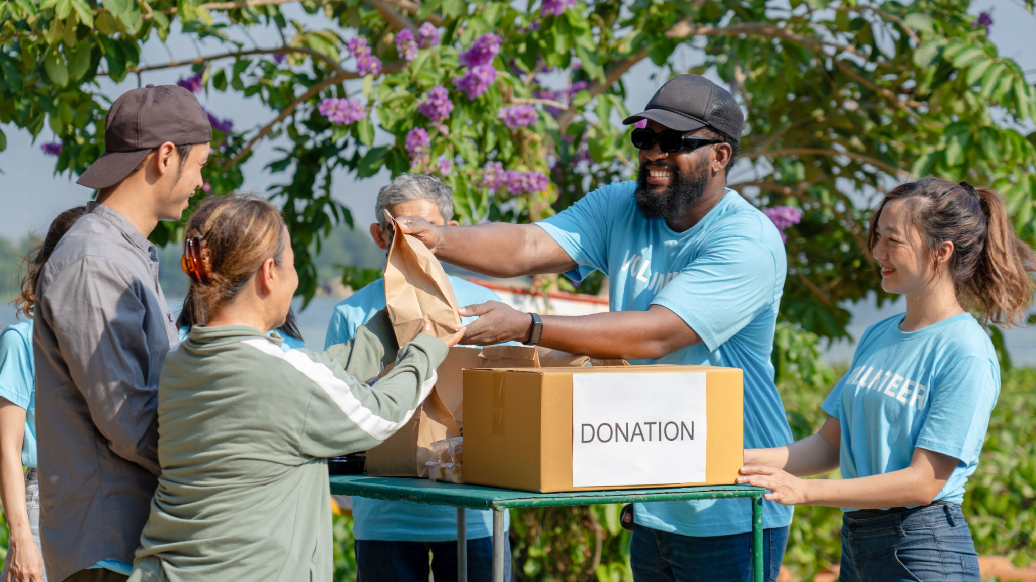 African man volunteer give some food in paper bag to poor people, raising money through donation box African man volunteer give some food in paper bag to poor people, raising money through donation box