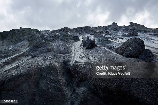 black and grey rock side and dramatic clouds - vulkanisch gesteente stockfoto's en -beelden