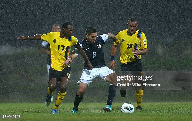 Clint Dempsey of the United States fights for a ball against Luke Anthony George and George Dublin of Antigua and Barbuda during a World Cup...