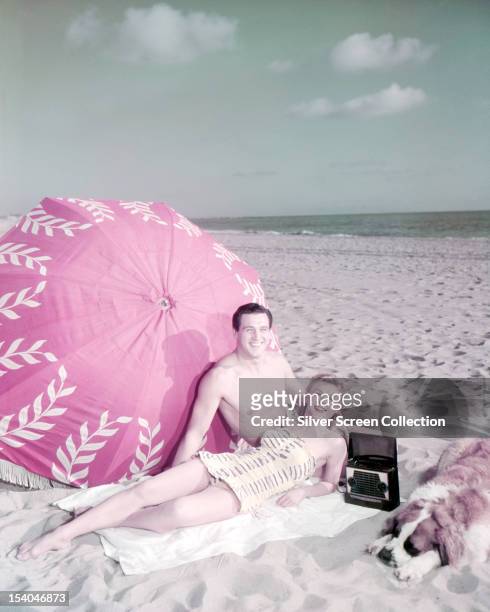 American actors Rock Hudson and Vera-Ellen on a beach with a dog, circa 1955.