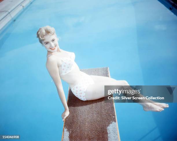 American singer and actress Shirley Jones sitting on a diving board in a red and white polka-dot bikini, circa 1955.