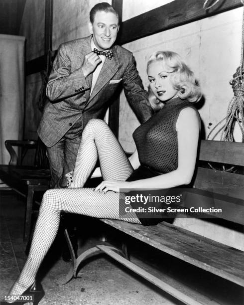 American actress and pin-up model Joi Lansing with an admirer, circa 1955. She is wearing shorts and fishnet stockings.