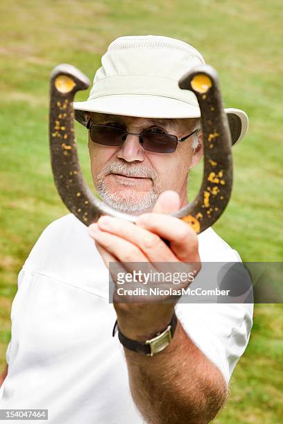 senior man playing horseshoes - horseshoe luck stock pictures, royalty-free photos & images