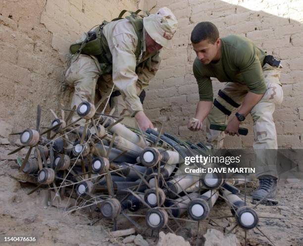 Navy AO2 Scott Bryant of Seattle, WA, and Chief Petty Officer Jon Scott of Virginia Beach, VA, wire C4 explosives to a pile of rockets and other...