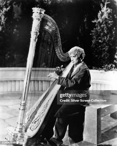 American comedian, actor and harpist Harpo Marx playing a harp in 'Animal Crackers', directed by Victor Heerman, 1930.