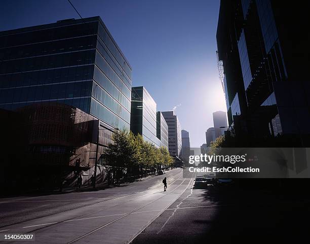 woman crossing empty street in melbourne at dawn - docklands melbourne stock-fotos und bilder