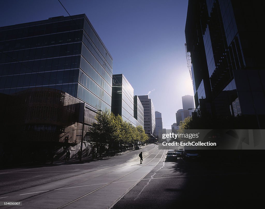 Woman crossing empty street in Melbourne at dawn