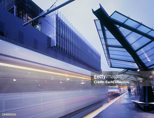 tram arriving at a modern tram stop in melbourne - tram stock pictures, royalty-free photos & images