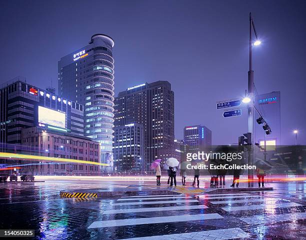 rainy evening with people waiting to cross street - korea city stockfoto's en -beelden