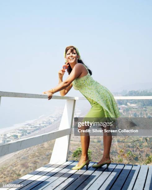 Italian actress Claudia Cardinale leaning on a balcony overlooking a beach, circa 1967.