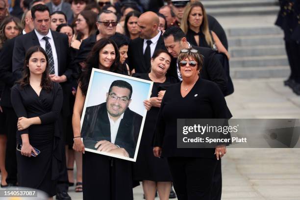 Family members carry a portrait of Augusto Acabou while attending the funeral for the Newark, NJ firefighter, who lost his life with fellow...