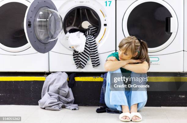 sad woman doing laundry in laundromat - bored housewife stock pictures, royalty-free photos & images