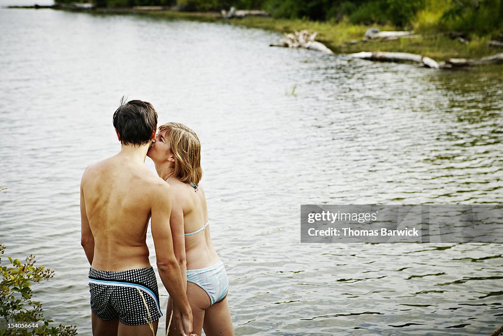 Couple standing by water woman kissing mans cheek