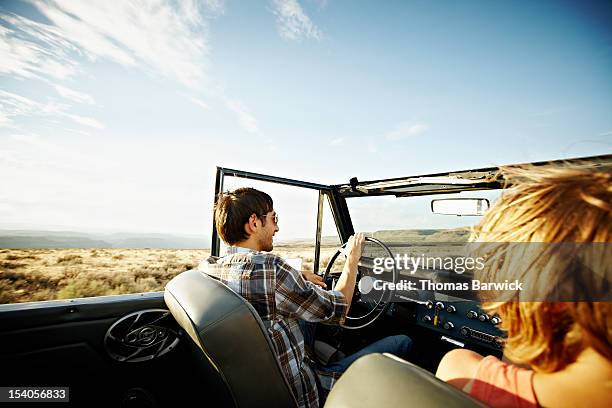 man smiling driving convertible on rural road - fahrspaß stock-fotos und bilder