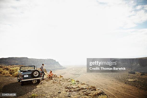 couple next to convertible on side of desert road - secluded couple stockfoto's en -beelden