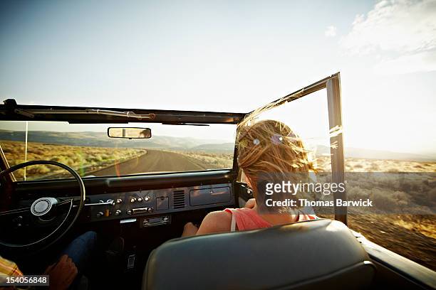 woman riding in convertible at sunset - incidental people stock pictures, royalty-free photos & images
