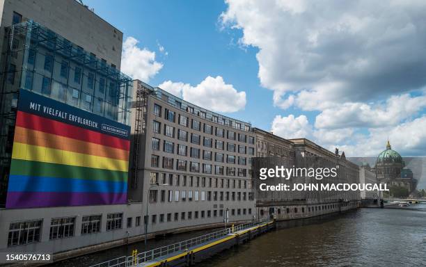 Giant billboard featuring a rainbow flag hangs on the river Spree-facing facade of the Haus der Deutschen Wirtschaft in Berlin on July 18, 2023. The...