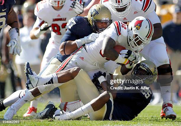 Senorise Perry of the Louisville Cardinals is tackled by Jason Hendricks and Aaron Donald of the Pittsburgh Panthers during the game on October 13,...