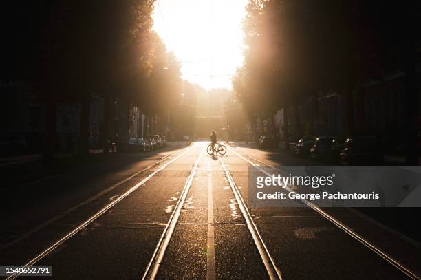 commuter with bicycle, crossing the city street with sunlight - amsterdam sunrise stockfoto's en -beelden