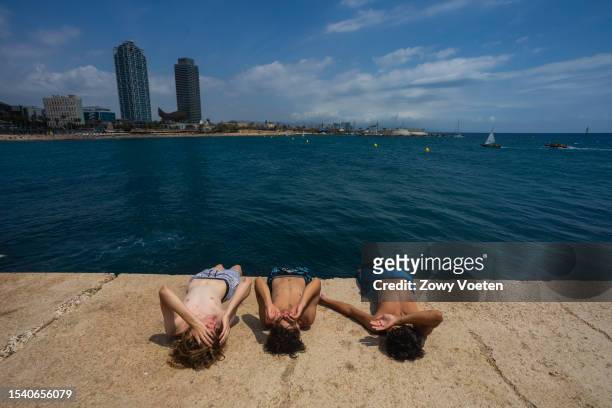 Young people enjoy the sun from the Barceloneta pier on July 13, 2023 in Barcelona, Spain. An area of high pressure, named Cerberus after the...