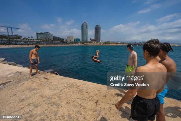 Young people enjoy jumping from the Barceloneta breakwater into the sea to withstand the midday heat on July 13, 2023 in Barcelona, Spain. An area of...