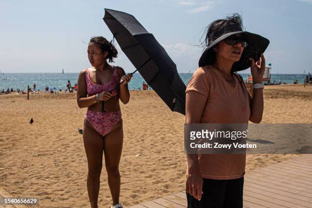 Tourist takes a black umbrella to the beach to cover herself from the sun and avoid getting burned at Barceloneta beach on July 13, 2023 in...