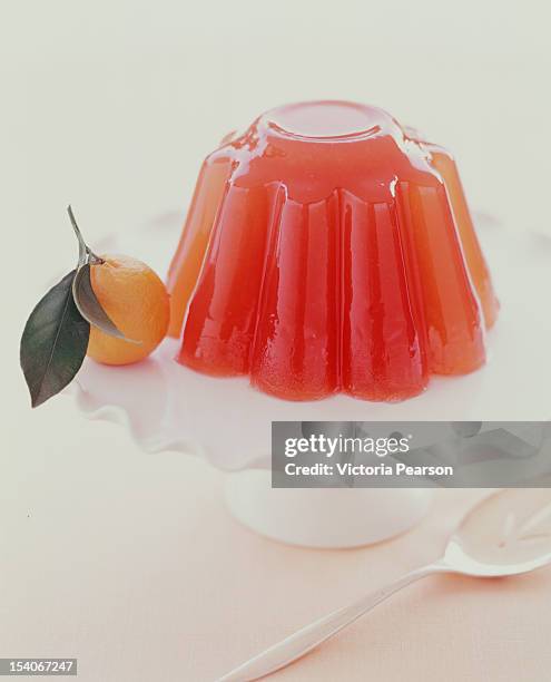 gelatin mold on platter with orange. - jello mold stock-fotos und bilder