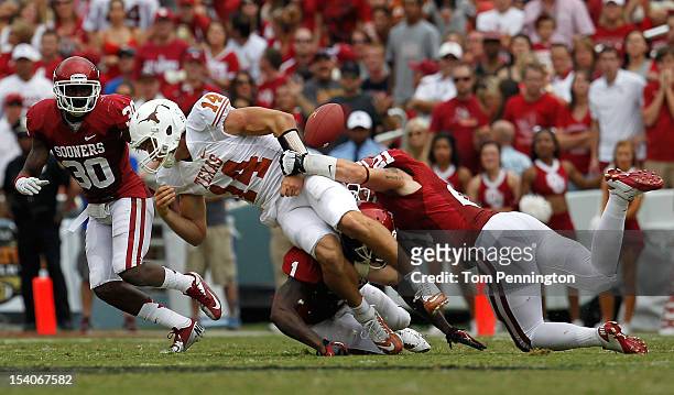 Quarterback David Ash of the Texas Longhorns fumbles the ball after being hit by Tom Wort of the Oklahoma Sooners and Tony Jefferson of the Oklahoma...