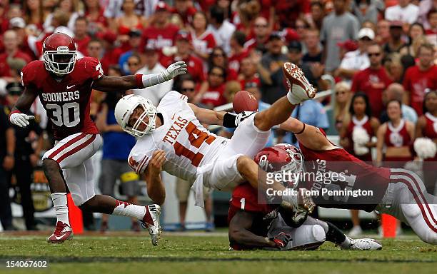 Quarterback David Ash of the Texas Longhorns fumbles the ball after being hit by Tom Wort of the Oklahoma Sooners and Tony Jefferson of the Oklahoma...