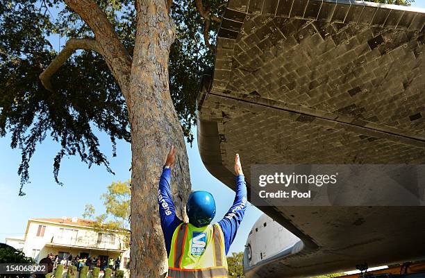 Worker guides NASA Space Shuttle Endeavour as it moves on Crenshaw Drive enroute to the California Science Center on October 13, 2012 in Inglewood,...