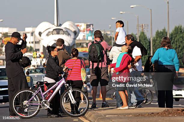 Spectators get a street level view of the space shuttle Endeavour as it pauses during its transport from Los Angeles International Airport to the...