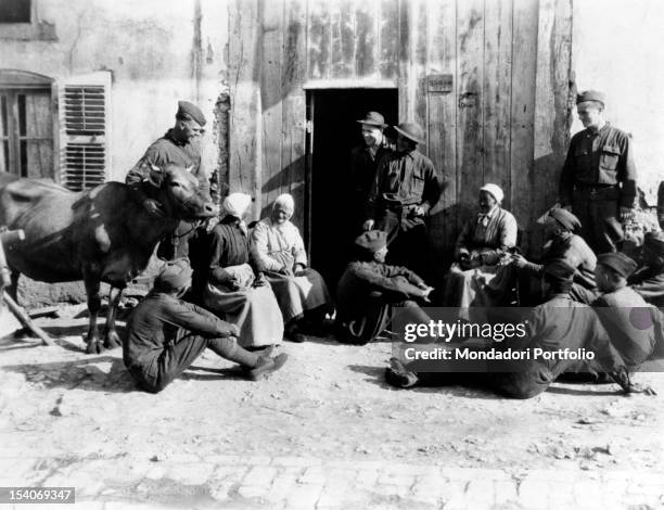 Soldiers chatting with some French peasants. France, 1918