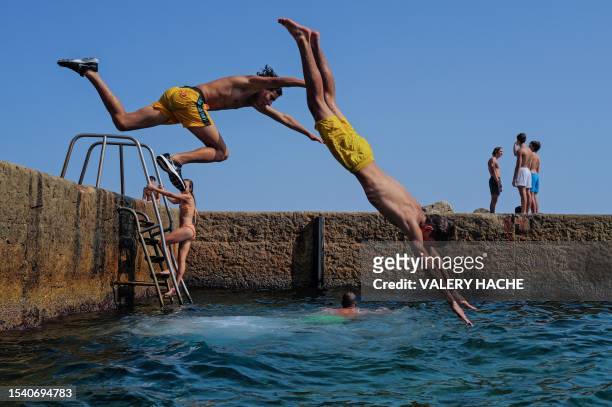 People jump in the Mediterranean sea on the french riviera city of Nice on July 18, 2023.