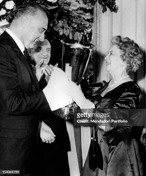 The Canadian businesswoman Elizabeth Arden receives from the French ambassador Bayens the Coupe du Bon Gout for creating the Memoire Cherie perfume....